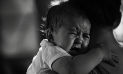 Infant with apnea crying on mothers shoulder