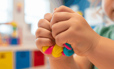 Child playing with squishy sensory materials like dough to practice saying “squish” and other /skw/ words.