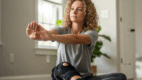 Young woman with hEDS wearing knee brace and stretching gently