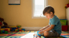 Child hyperfocused on lining up toy cars during play.