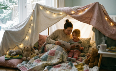 Child and parent sitting inside a cozy blanket fort reading a book during winter indoor play.