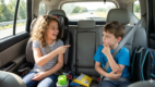 Siblings sitting in the back seat playing a verbal road trip game together