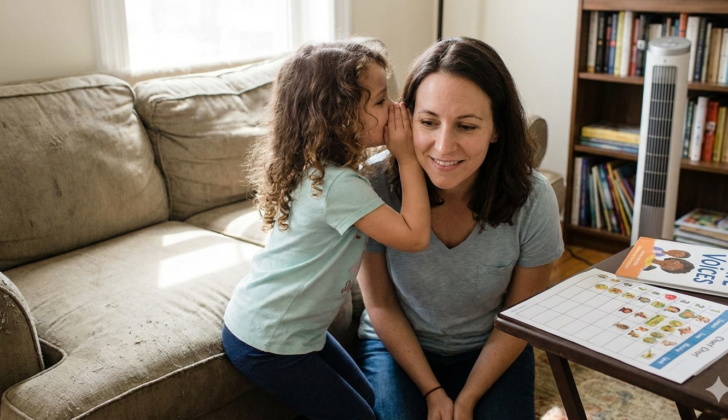 Child whispering to parent as a small step forward in selective mutism support.